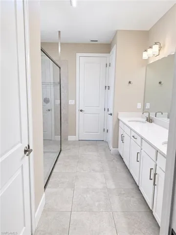 Double vanity with white cabinetry, light-toned countertops, and brushed nickel hardware