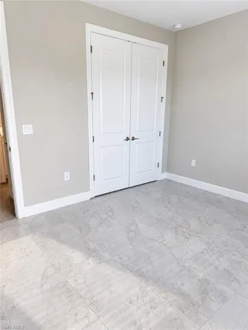 Light gray wall color, white trim, recessed ceiling lighting, light-toned tile flooring, and double panel doors with dark hardware