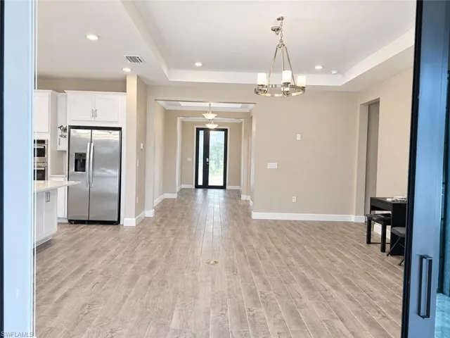 Open concept living area featuring wood-finish flooring, recessed lighting, and a tray ceiling