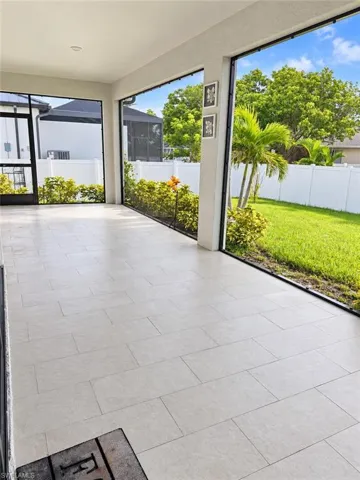 Screened-in outdoor living space featuring light-toned rectangular tile flooring