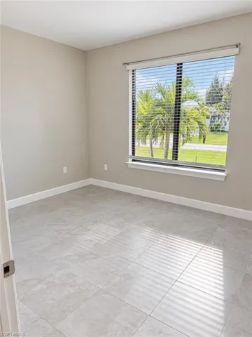 Rectangular window with horizontal blinds, light-toned walls, white baseboards, and large format tile flooring