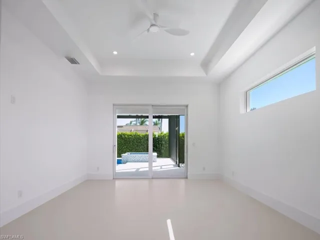Empty room with a tray ceiling, ceiling fan, and recessed lighting
