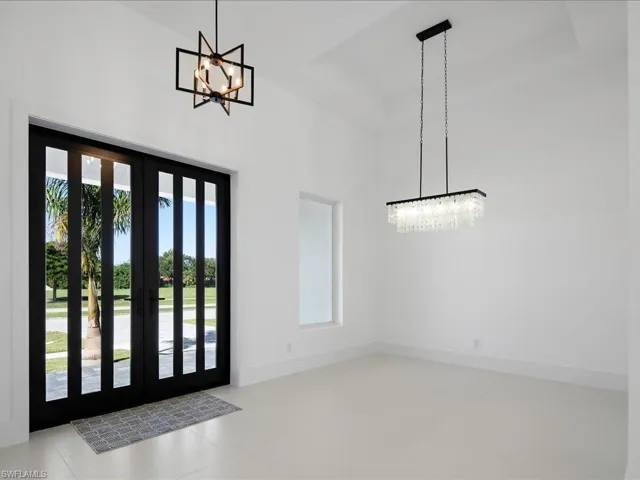 Entrance foyer with a chandelier, a tray ceiling, and light tile patterned floors