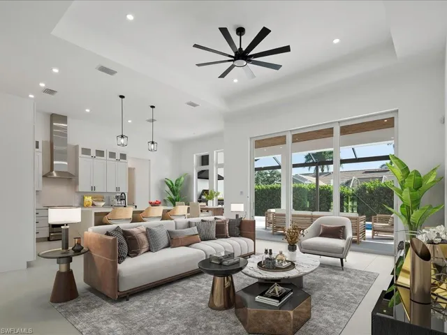 Living room with a raised ceiling, recessed lighting, ceiling fan, a towering ceiling, and finished concrete flooring