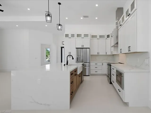 Kitchen featuring glass insert cabinets, light stone counters, white cabinets, recessed lighting, and appliances with stainless steel finishes