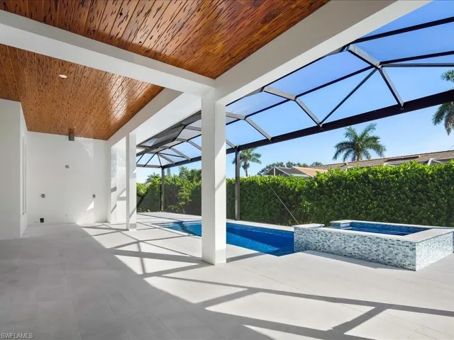 View of pool with glass enclosure, a patio area, a sunroom, and a pool with connected hot tub