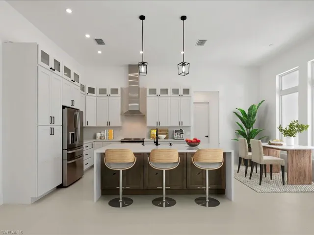 Kitchen with stainless steel fridge, glass insert cabinets, decorative light fixtures, a breakfast bar, and light stone countertops