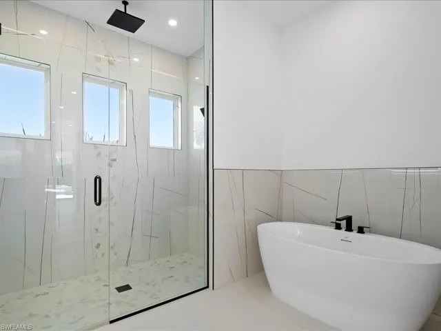 Full bathroom with tile walls, a freestanding bath, a marble finish shower, and recessed lighting