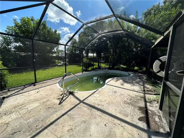 View of swimming pool featuring glass enclosure, a lawn, and a patio
