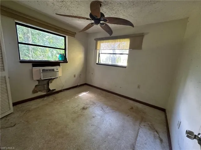 Unfurnished bedroom with ceiling fan, cooling unit, and a textured ceiling