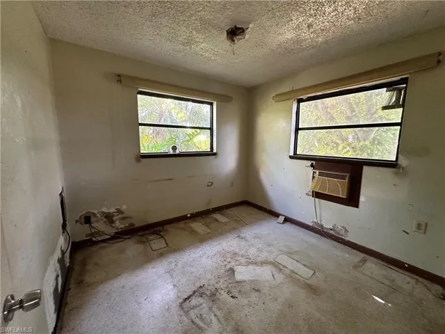 Unfurnished room featuring a textured ceiling and cooling unit