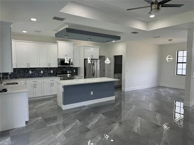 Kitchen featuring appliances with stainless steel finishes, a center island, white cabinets, and pendant lighting