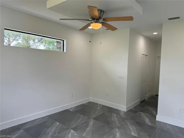 Unfurnished room featuring ceiling fan and dark tile floors