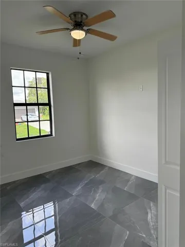 Spare room featuring dark tile floors and ceiling fan