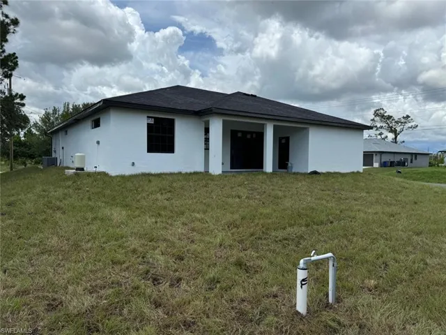Back of house featuring central AC unit and a yard