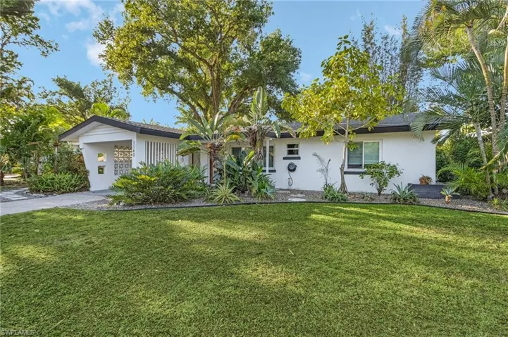 Mid-Century Architecture  home featuring a front yard, driveway, and stucco siding