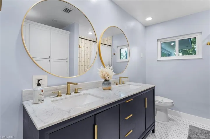 Full bathroom with toilet, a double sink, storage closets