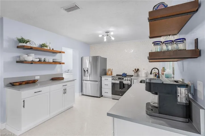 Kitchen featuring white cabinetry, open shelves, stainless steel appliances, a deep sink
