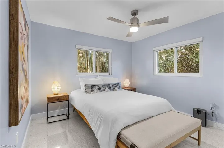 Bedroom with two windows, backyard views, a ceiling fan, and terrazo floors