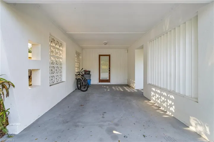 View of exterior entry with an attached carport and a patio