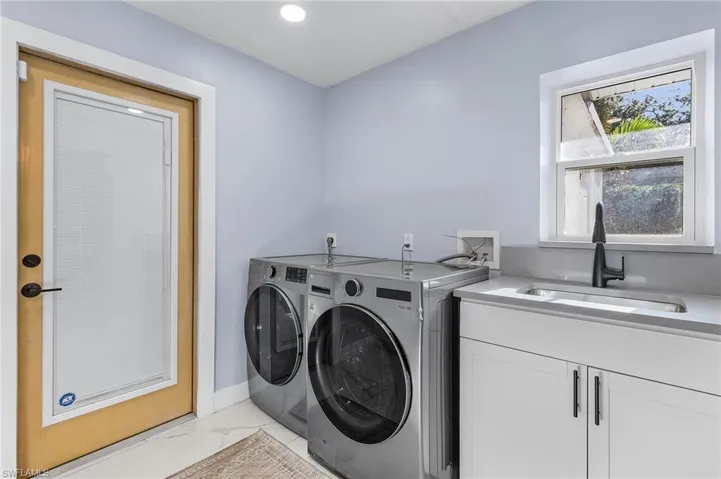 Laundry area featuring washer and clothes dryer, recessed lighting, marble finish floor, a sink, and cabinet space / pantry