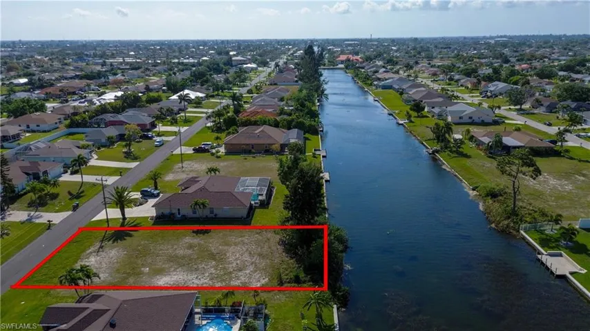 Aerial view of residential area featuring property parcel outlined and a nearby body of water
