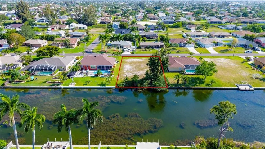 Aerial view of residential area featuring a large body of water and property boundaries highlighted