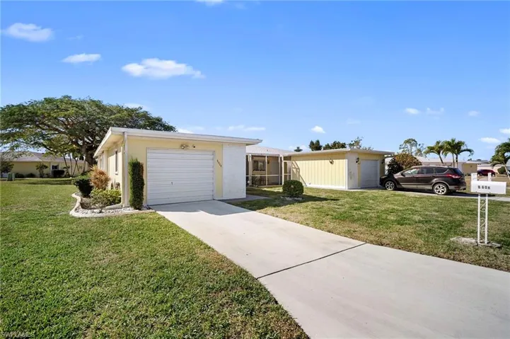 View of front of property featuring a front yard, a garage, and concrete driveway