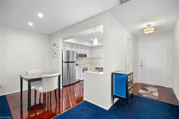 Kitchen with light countertops, pendant lighting, stainless steel appliances, dark wood finished floors, and white cabinets
