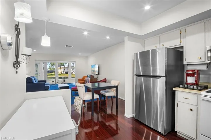 Kitchen featuring stainless steel appliances, light countertops, open floor plan, dark wood-type flooring, and pendant lighting