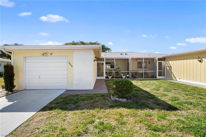 Ranch-style home with a front lawn, a sunroom, concrete driveway, a garage, and brick siding