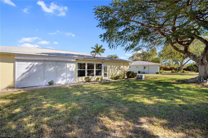 Rear view of house with a lawn and stucco siding