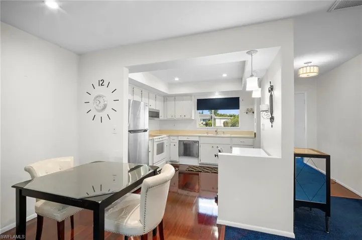 Kitchen with light countertops, white cabinets, stainless steel appliances, dark wood finished floors, and pendant lighting