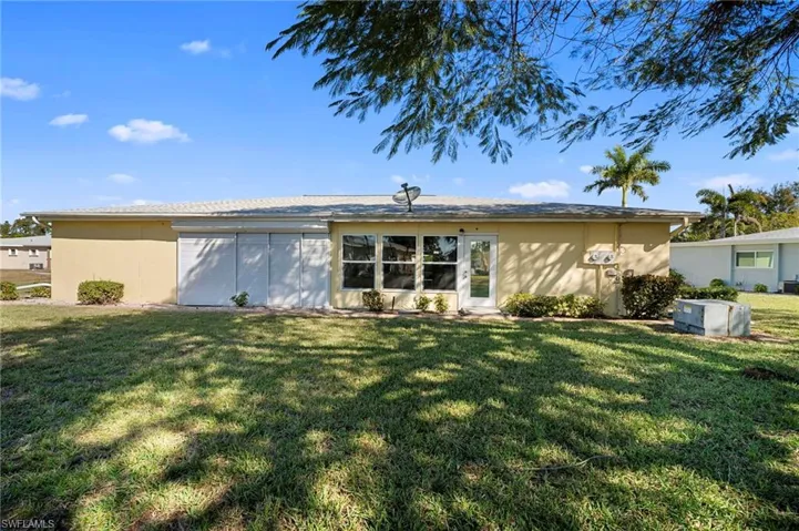 Back of property featuring a lawn and stucco siding