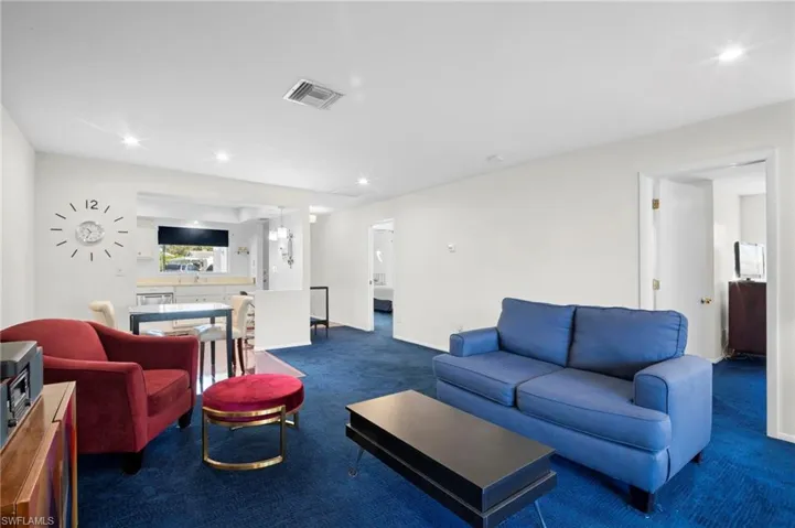 Living area with recessed lighting and dark carpet