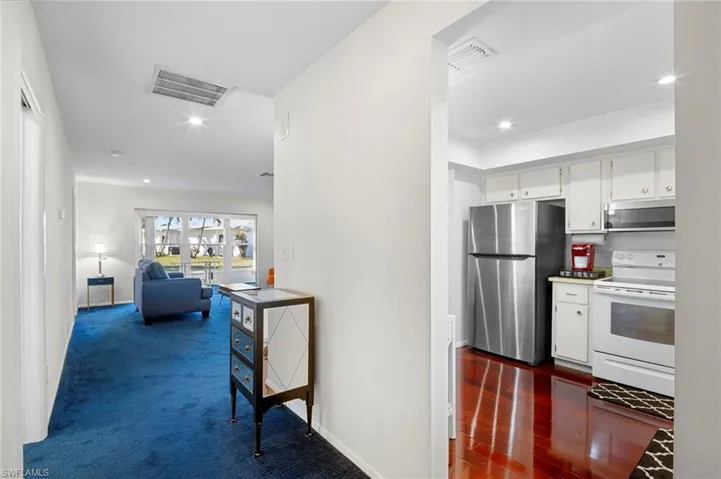 Kitchen with stainless steel appliances, white cabinets, recessed lighting, dark carpet, and open floor plan
