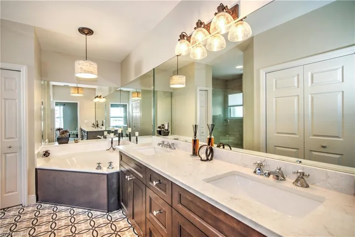 Wood cabinetry from Naples kitchen and bath, double sink quartz countertops, large soaking tub and generously sized fully tiled shower with frameless glass shower door - Moen rain shower head