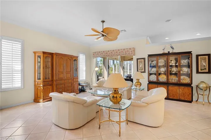 Living room featuring crown molding, a ceiling fan, and light tile patterned floors