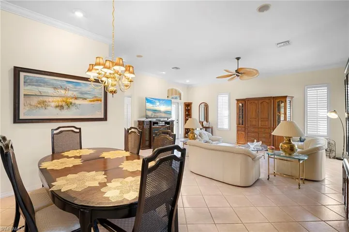 Dining space with light tile patterned flooring, crown molding, hanging lights, and ceiling fan