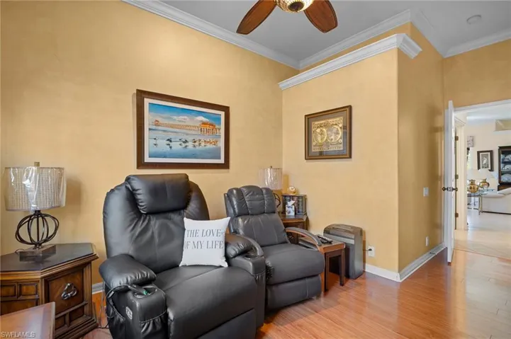 Living area with wood finished floors, a ceiling fan, and crown molding