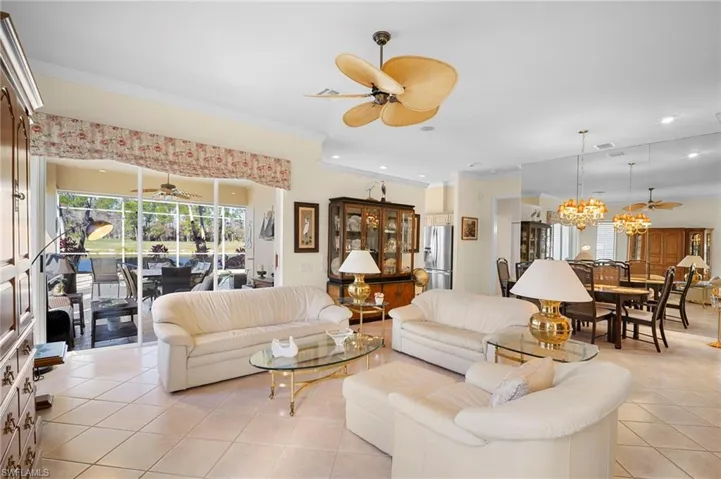 Living area with ceiling fan, crown molding, light tile patterned flooring, hanging lights, and a sunroom