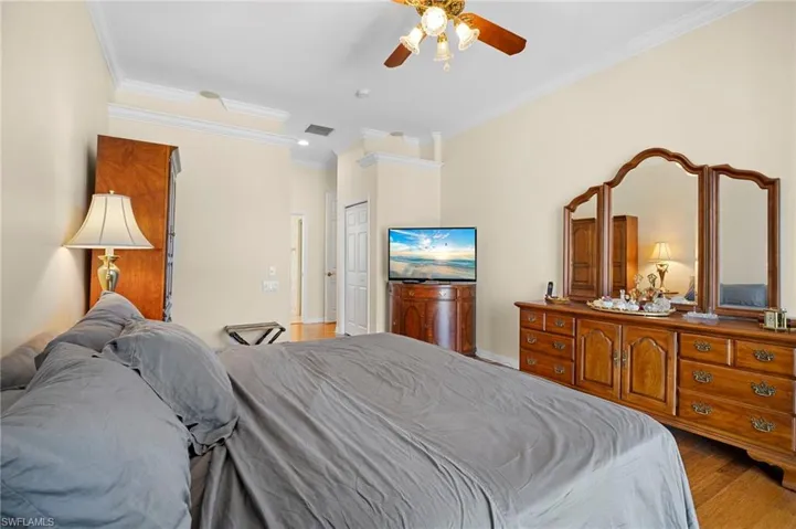Bedroom with crown molding, ceiling fan, light wood-type flooring, and a closet