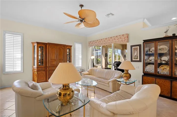 Living area with light tile patterned flooring, crown molding, and a ceiling fan