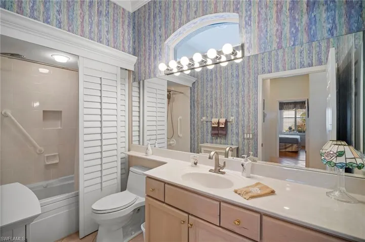 Ensuite bathroom with vanity, wallpapered walls, and shower / bath combination