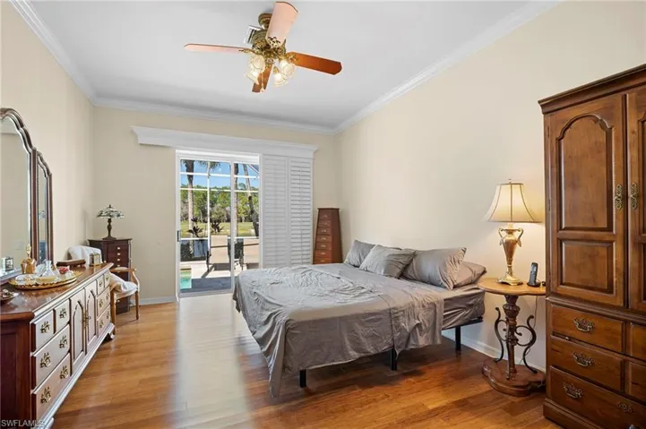 Bedroom with ornamental molding, access to exterior, wood finished floors, and ceiling fan