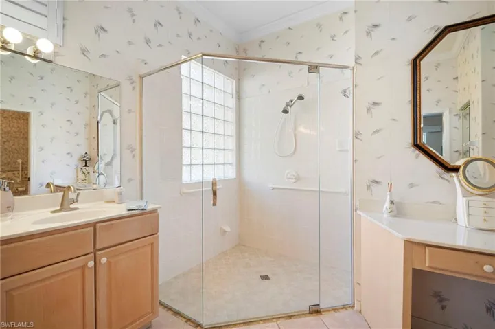 Full bathroom with wallpapered walls, vanity, a shower stall, and ornamental molding
