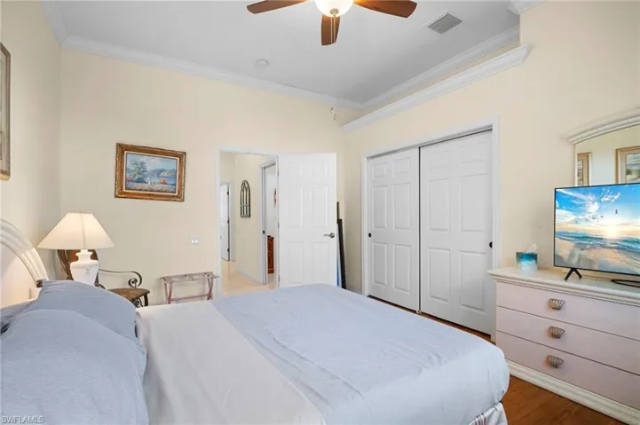 Bedroom featuring ornamental molding, a ceiling fan, a closet, and light wood finished floors