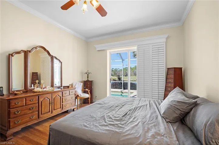 Bedroom with access to exterior, ornamental molding, a ceiling fan, and dark wood-style flooring