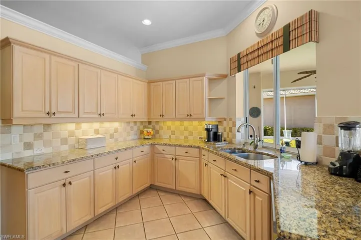 Kitchen with open shelves, light stone countertops, light wood finish cabinets, backsplash, and crown molding