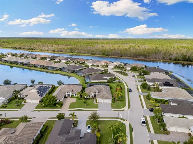 Aerial view of residential area with a nearby body of water and a forest
